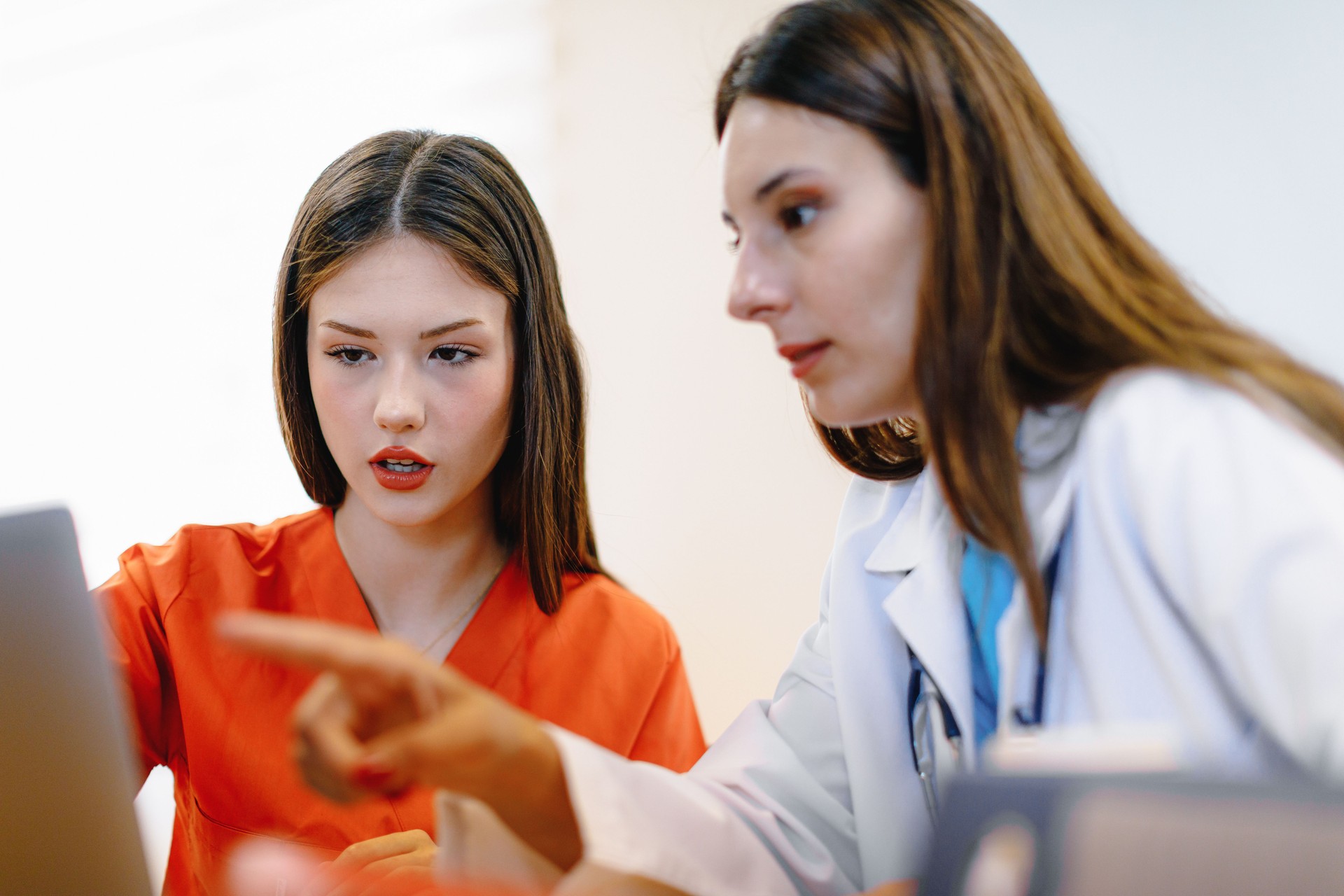 During a meeting, two young female healthcare workers are engaged in a thoughtful discussion